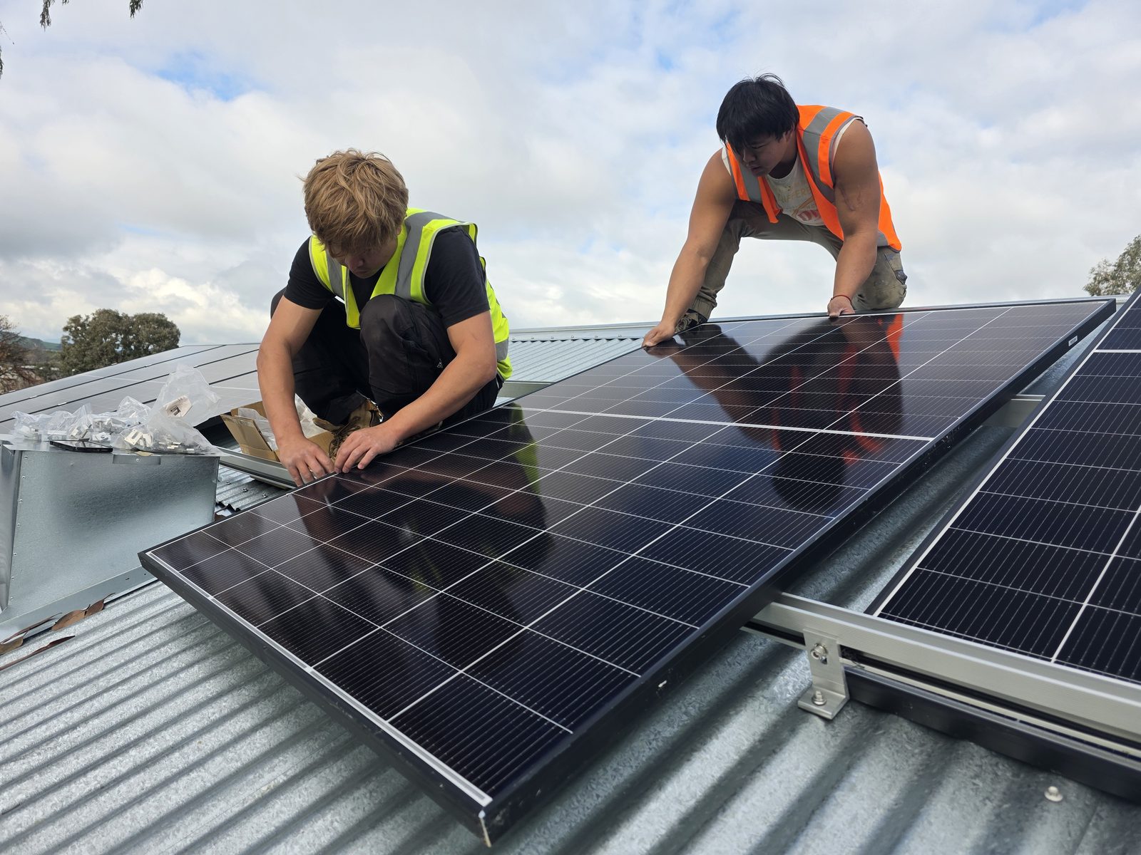Two CEC-accredited E3 Energy installers fitting solar panels on the museum roof