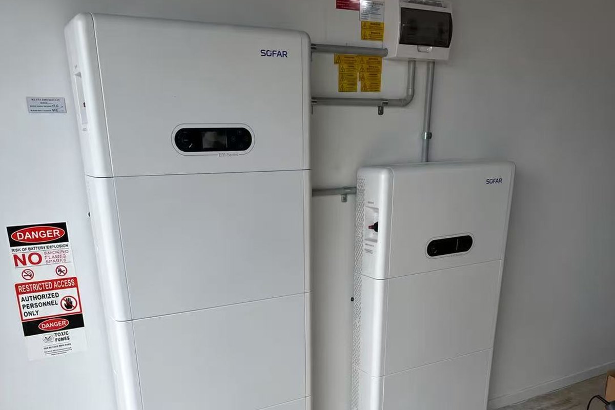 An E3 Energy SOFAR installation: two white SOFAR battery stacks with an ESI hybrid inverter display in a garage beside the switchboard