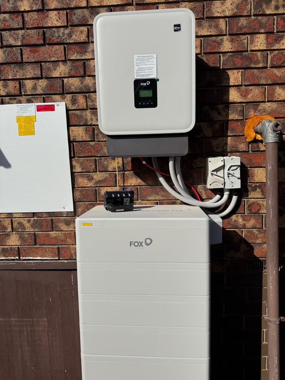 Fox ESS battery stack and hybrid inverter installed by E3 Energy on a brick wall at a Melbourne home